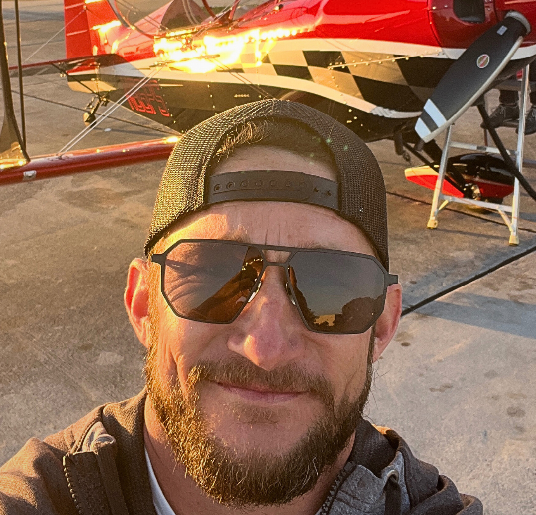 Pilot wearing SkyRift sunglasses standing near aircraft on the ramp before flight
